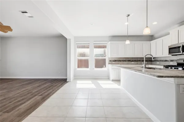 a large kitchen with granite countertop a stove a sink and a microwave