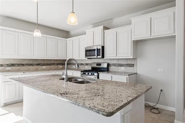 a kitchen with granite countertop a sink a counter top space appliances and cabinets