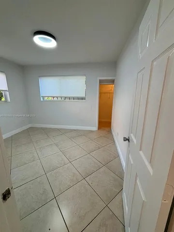 a view of a white house with a big yard plants and large trees