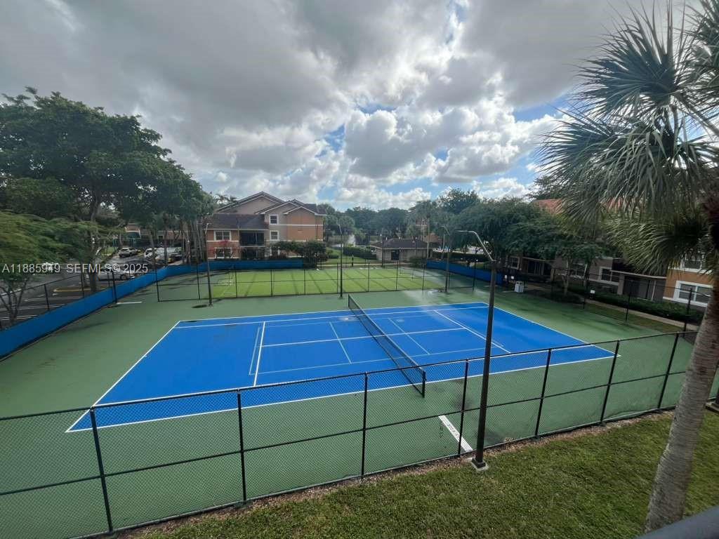 8821 Wiles Road, Unit 102 Coral Springs, FL 33067 - Photo 7 of 10 a view of a tennis ground with a large trees in the background