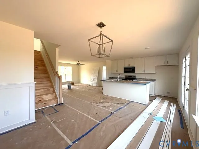 a view of a kitchen with kitchen island wooden floor and stainless steel appliances