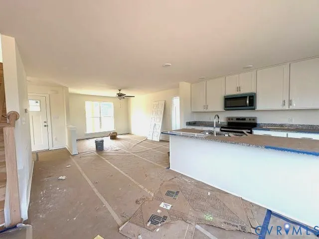 a living room with stainless steel appliances kitchen island granite countertop a refrigerator a stove top oven a sink and dishwasher