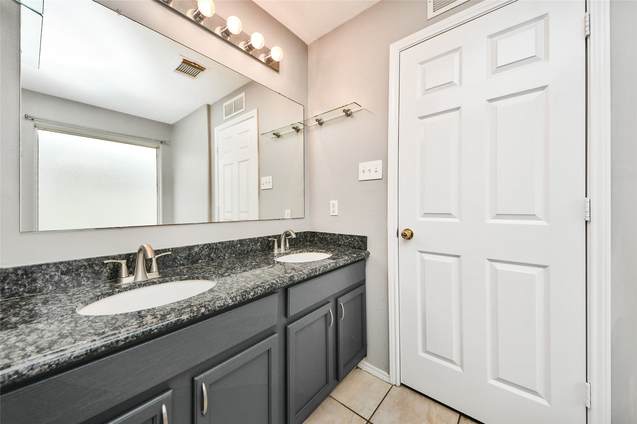 24019 Kingbriar Drive Spring, TX 77373 - Photo 33 of 41 A closer look at the double vanity featuring dual sinks and a large mirror, complemented by modern lighting and neutral tones.