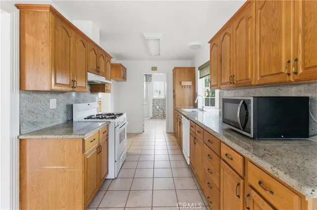 a large kitchen with stainless steel appliances granite countertop a stove a sink and a microwave