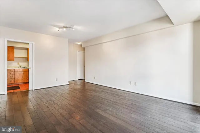 an empty room with wooden floor and natural light