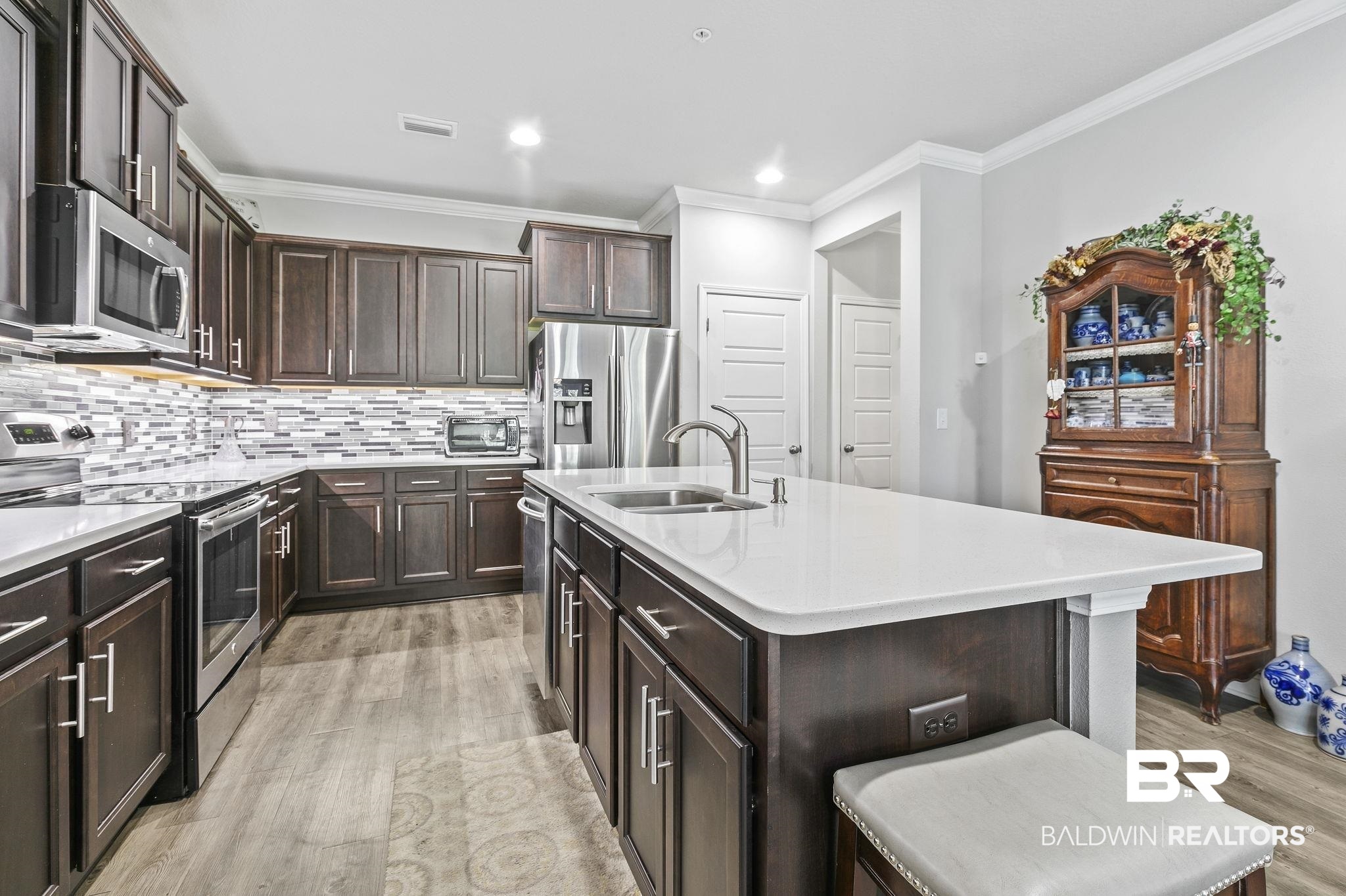 6867 Spaniel Drive, Unit B Daphne, AL 36527 - Photo 11 of 36 Kitchen featuring sink, stainless steel appliances, a kitchen island with sink, a breakfast bar, and light wood-type flooring
