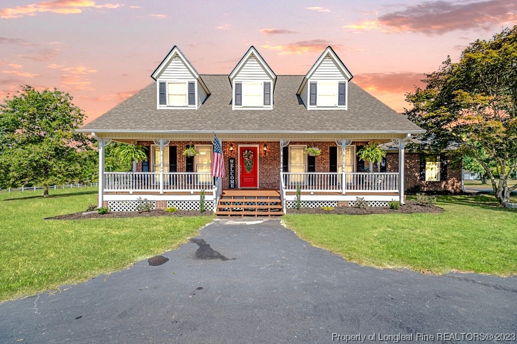 a view of a house with a yard and a large tree