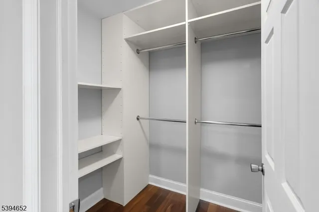 a walk in closet with wooden floor