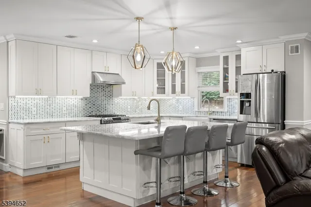 a kitchen with stainless steel appliances granite countertop a stove a refrigerator a sink a dining table and chairs with wooden floor