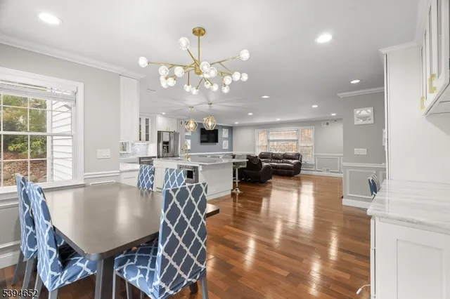 a view of a dining room and livingroom with furniture wooden floor a chandelier