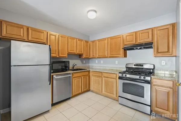 a kitchen with stainless steel appliances granite countertop a refrigerator sink stove and cabinets