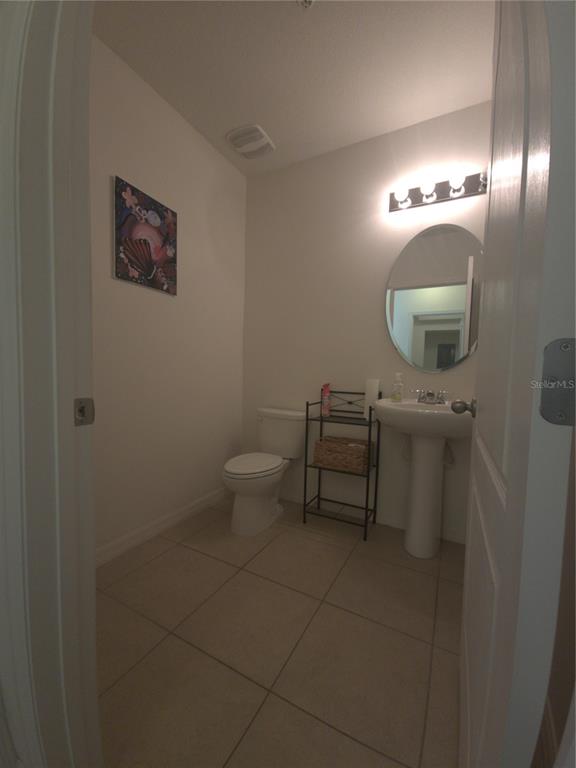 3724 Seneca Club Loop, Unit 41103 Orlando, FL 32808 - Photo 11 of 27 a bathroom with a toilet a sink and mirror