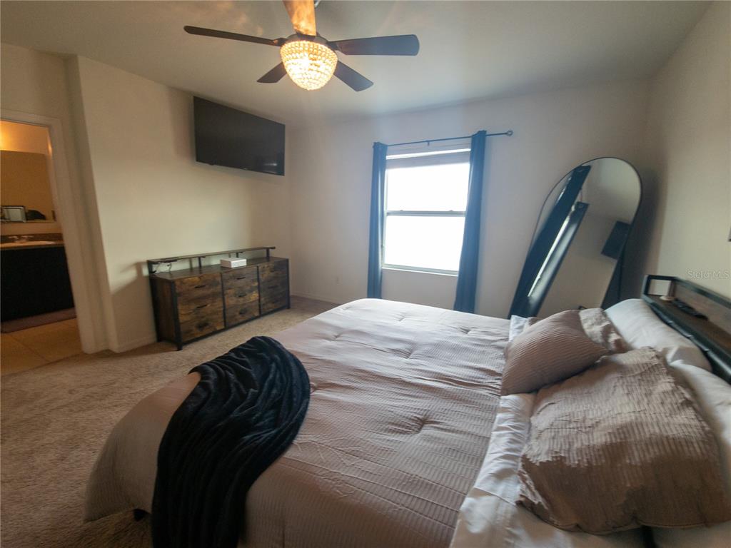 3724 Seneca Club Loop, Unit 41103 Orlando, FL 32808 - Photo 21 of 27 a bedroom with a bed and a flat tv screen on a dresser
