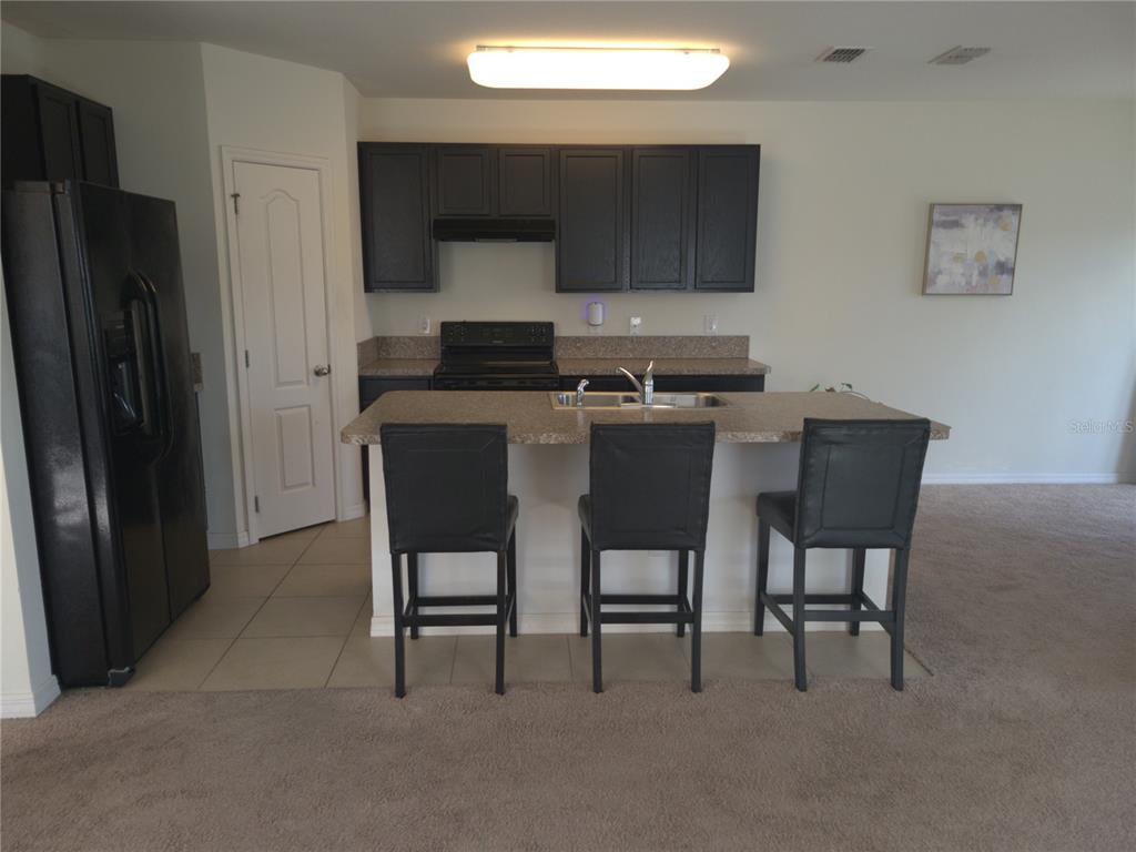 3724 Seneca Club Loop, Unit 41103 Orlando, FL 32808 - Photo 7 of 27 a kitchen with stainless steel appliances a table chairs and a refrigerator