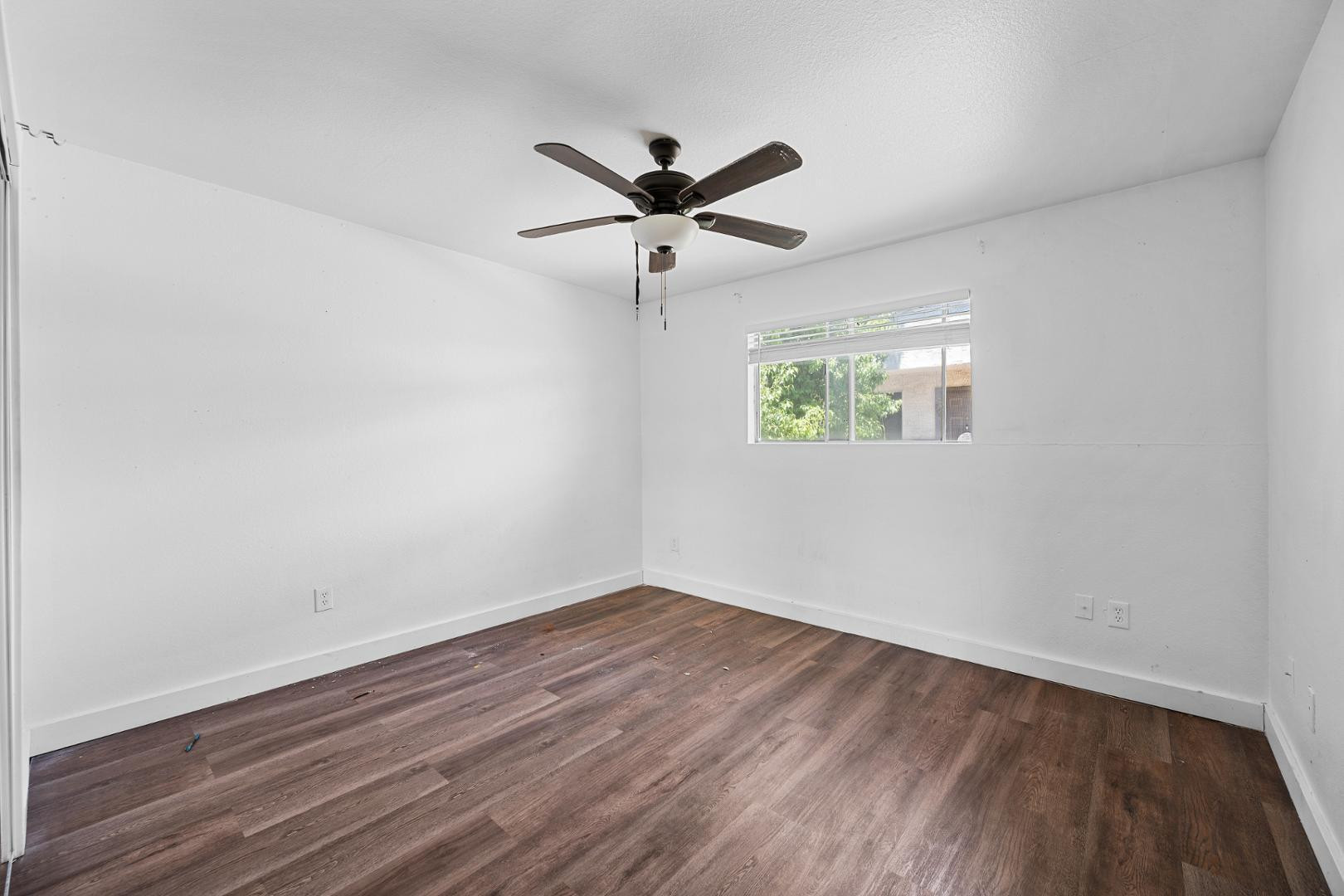 18202 North Cave Creek Road, Unit 252 Phoenix, AZ 85032 - Photo 7 of 15 an empty room with wooden floor ceiling fan and windows