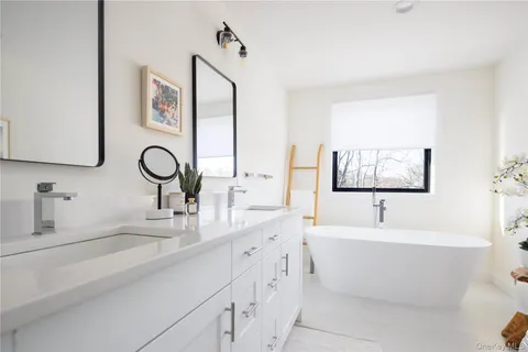 a bathroom with a double vanity sink mirror and bathtub