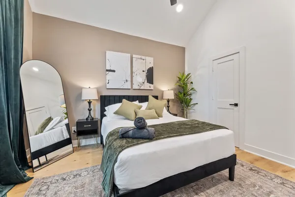 a bedroom with a bed a mirror and lamp