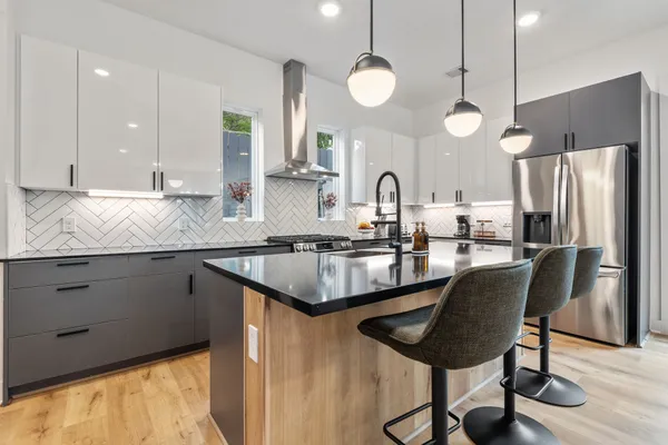 a kitchen with stainless steel appliances granite countertop a sink a stove a refrigerator and island with wooden floor