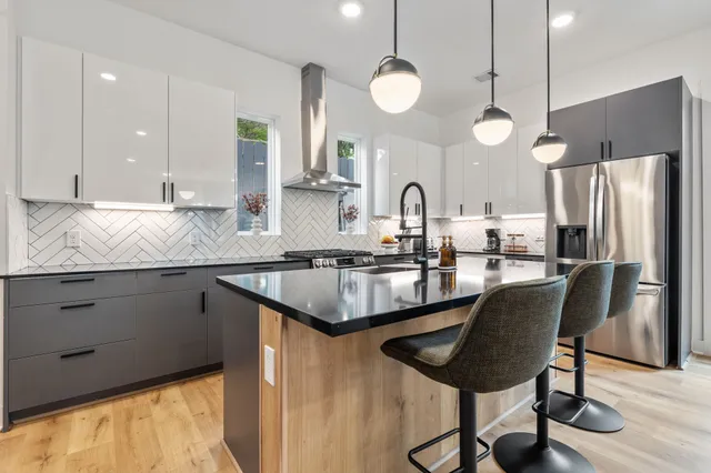 a kitchen with stainless steel appliances granite countertop a sink a stove a refrigerator and island with wooden floor