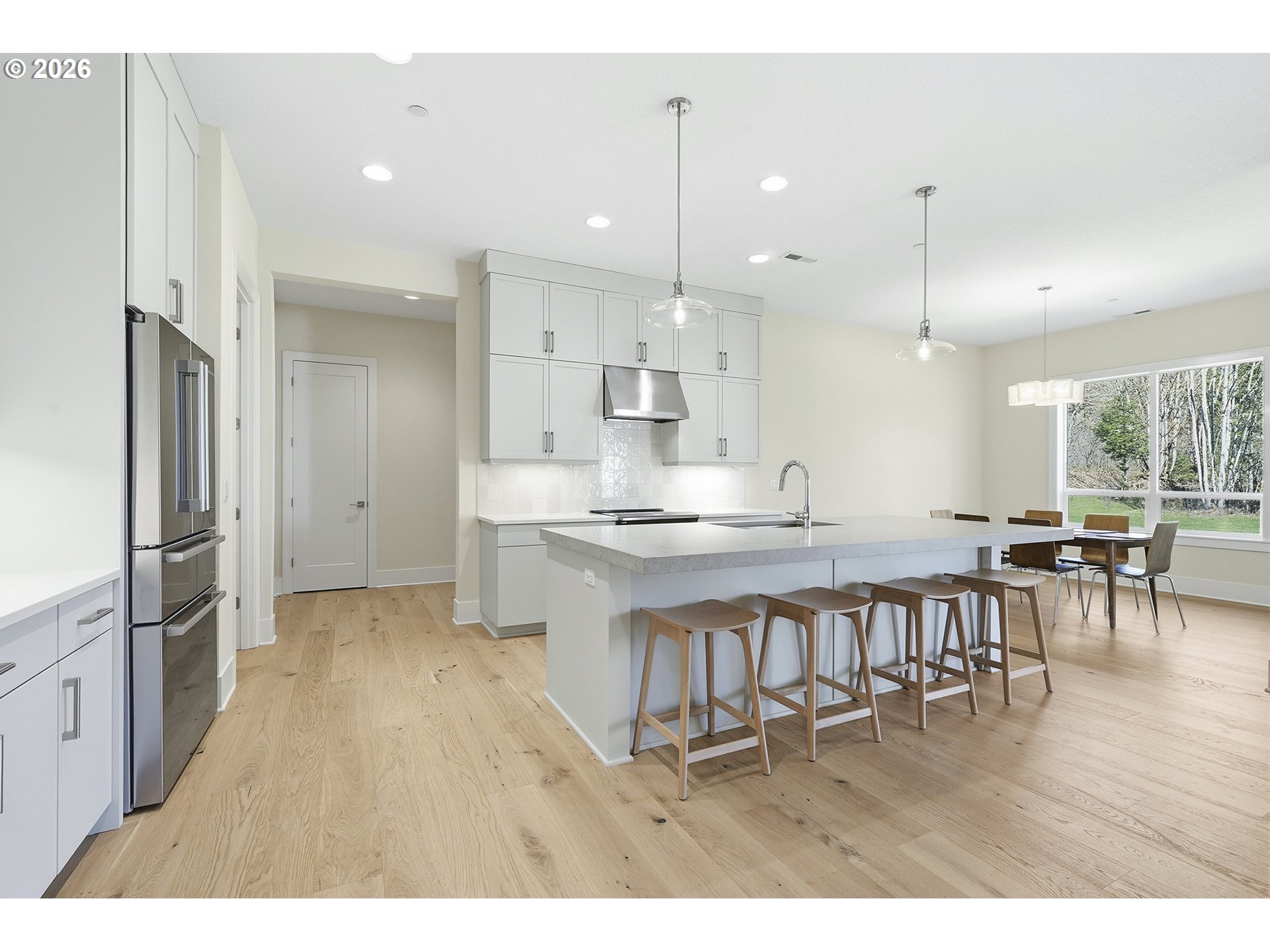 18771 Northwest Collins Road North Plains, OR 97133 - Photo 11 of 48 a open kitchen with stainless steel appliances granite countertop a kitchen island a stove a refrigerator a sink a dining table and chairs with wooden floor