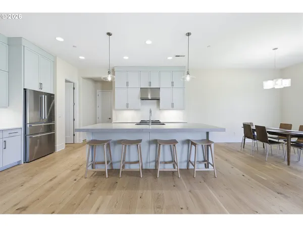 a kitchen with kitchen island a dining table chairs stainless steel appliances and cabinets