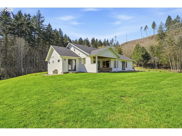 a view of a house with a yard and a large tree