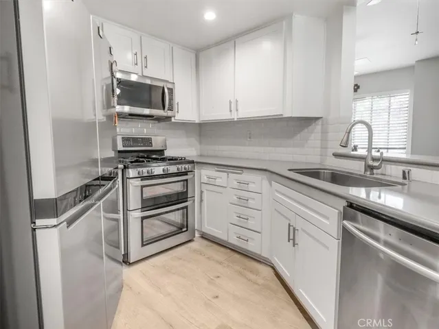 a kitchen with cabinets stainless steel appliances and a sink