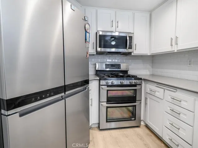 a kitchen with white cabinets and stainless steel appliances