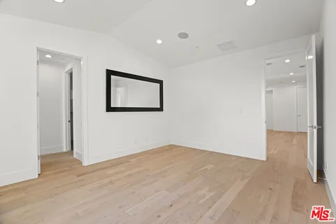 a view of an empty room with wooden floor and a painting