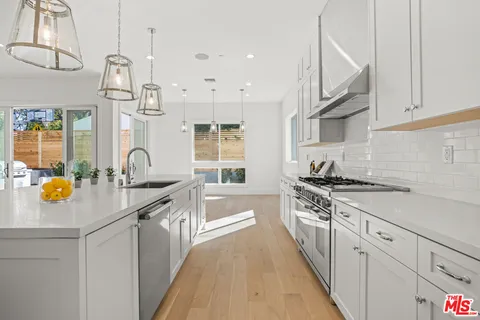 a kitchen with stainless steel appliances granite countertop a sink a stove and a wooden floors