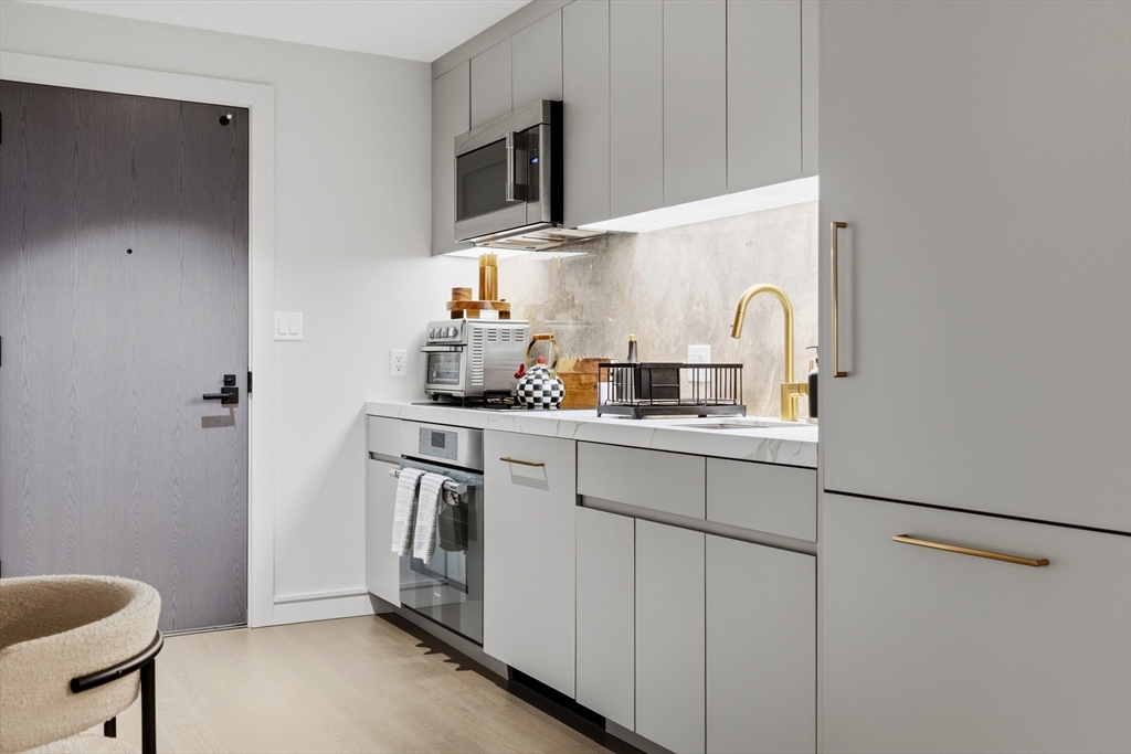 55 Lagrange Street, Unit 309 Boston, MA 02111 - Photo 7 of 20 a kitchen with stainless steel appliances a sink and a refrigerator
