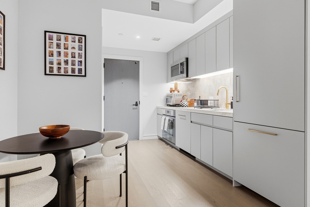 55 Lagrange Street, Unit 309 Boston, MA 02111 - Photo 8 of 20 a kitchen with stainless steel appliances cabinets and chairs