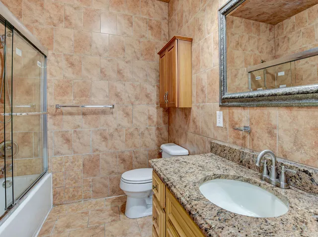 a bathroom with a granite countertop sink a toilet and shower