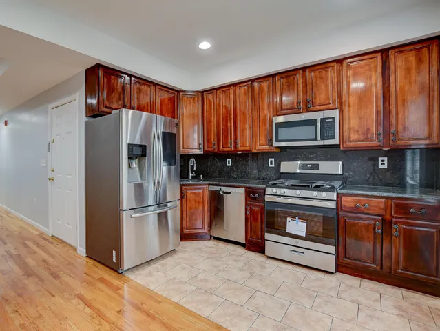 a kitchen with stainless steel appliances granite countertop a refrigerator stove top oven and sink