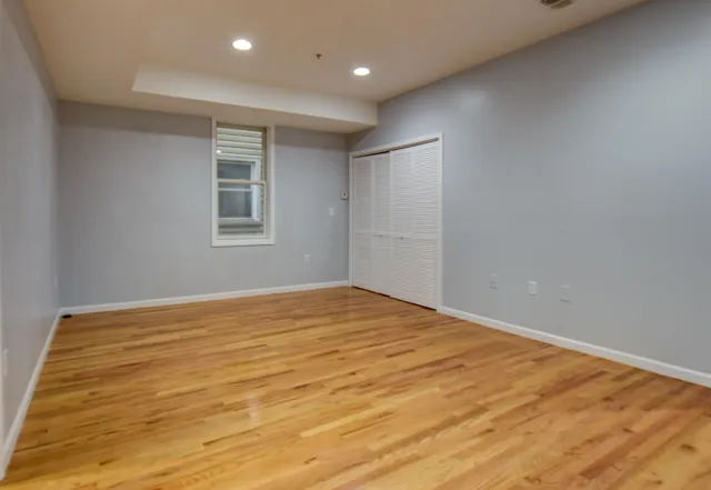 a view of empty room with wooden floor and fan