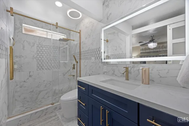 a bathroom with a granite countertop sink a toilet a mirror and shower