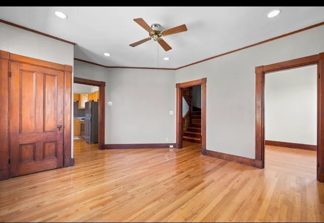 an empty room with wooden floor and a ceiling fan