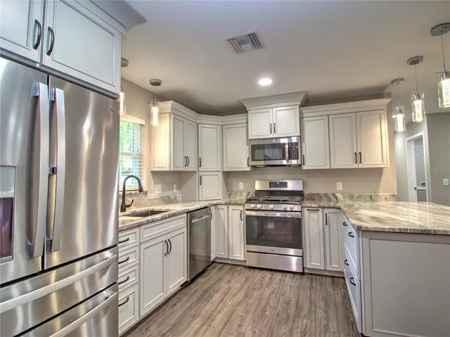 a kitchen with stainless steel appliances granite countertop a sink stove and refrigerator