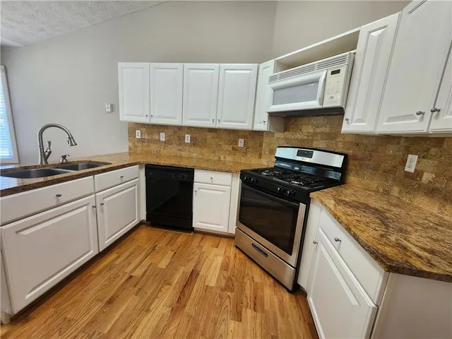 a kitchen with stainless steel appliances granite countertop a stove sink and cabinets