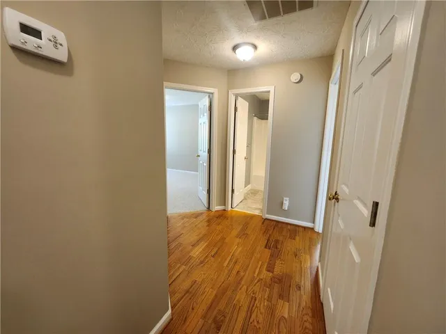 a view of a hallway with wooden floor and closet area