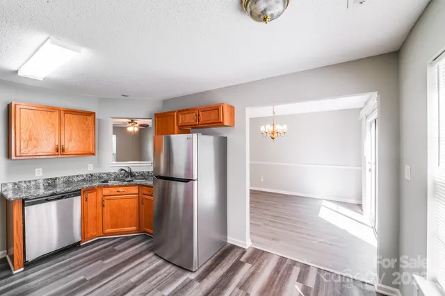 a kitchen with refrigerator and wooden floor
