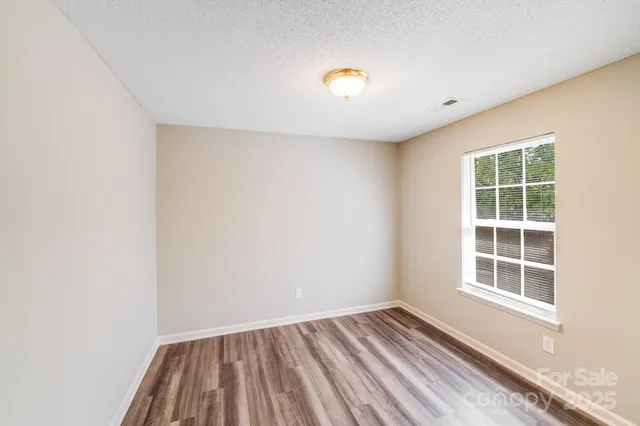 an empty room with wooden floor fan and windows
