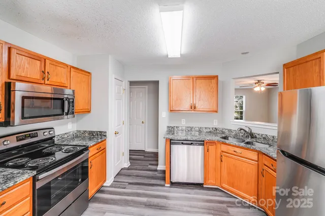 a kitchen with stainless steel appliances granite countertop a stove a sink and a refrigerator