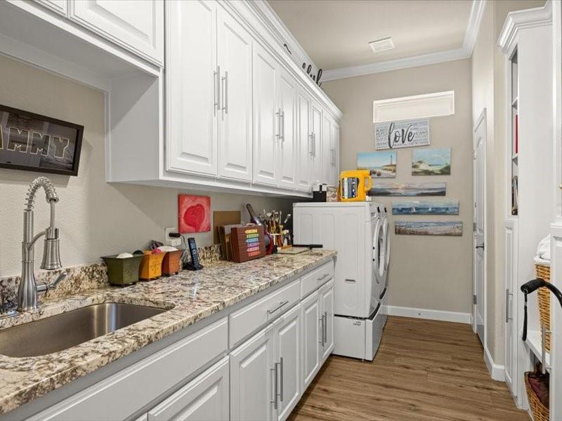 3510 Fountain Way Granbury, TX 76049 - Photo 15 of 27 Washroom with crown molding, light wood-type flooring, cabinet space, and separate washer and dryer