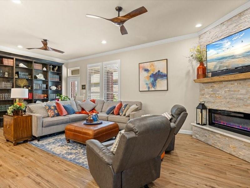 3510 Fountain Way Granbury, TX 76049 - Photo 5 of 27 Living room featuring a stone fireplace, crown molding, ceiling fan, light wood-type flooring, and recessed lighting