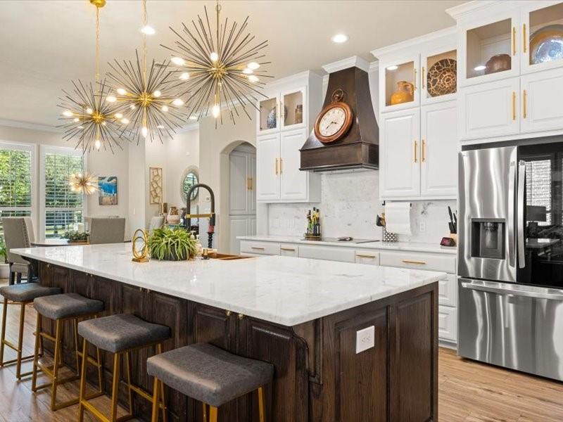 3510 Fountain Way Granbury, TX 76049 - Photo 8 of 27 Kitchen featuring dark brown cabinets, white cabinetry, arched walkways, stainless steel fridge, and decorative light fixtures