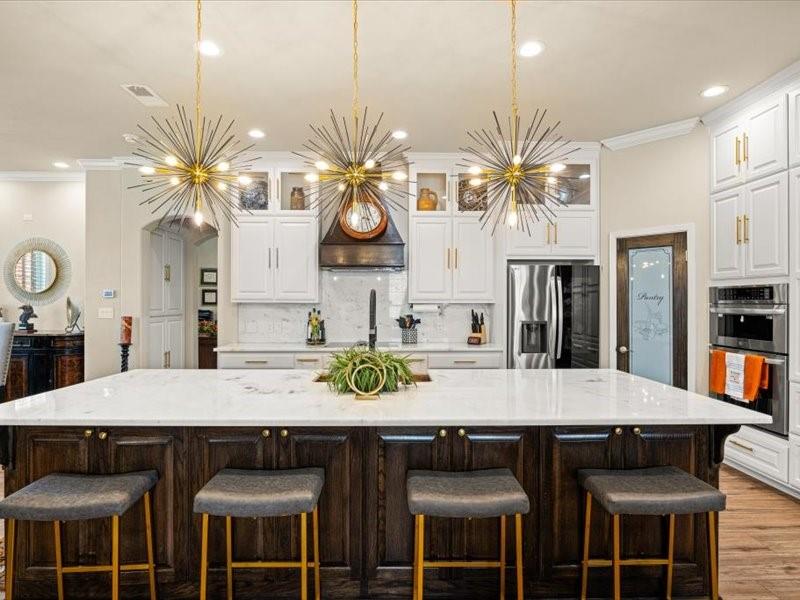 3510 Fountain Way Granbury, TX 76049 - Photo 9 of 27 Kitchen with crown molding, white cabinets, dark brown cabinetry, a spacious island, and tasteful backsplash