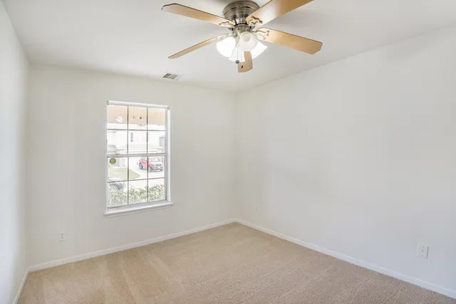 an empty room with windows and fan