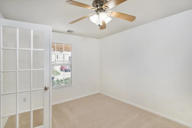 an empty room with a ceiling fan and window