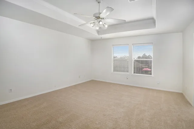 an empty room with a chandelier fan and windows